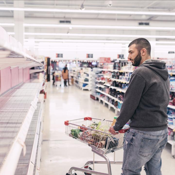 Man in grocery story looking at empty shelves