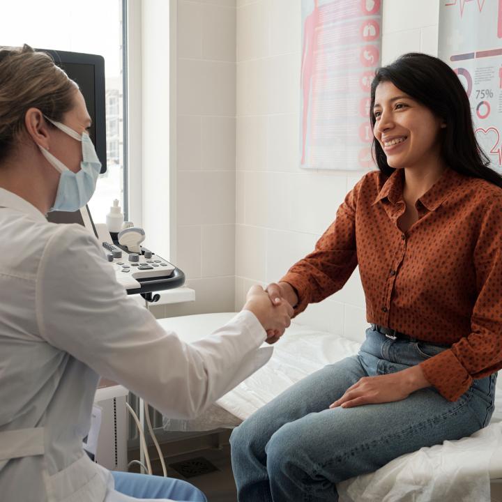 Smiling Latina shaking hands with her doctor at appointment