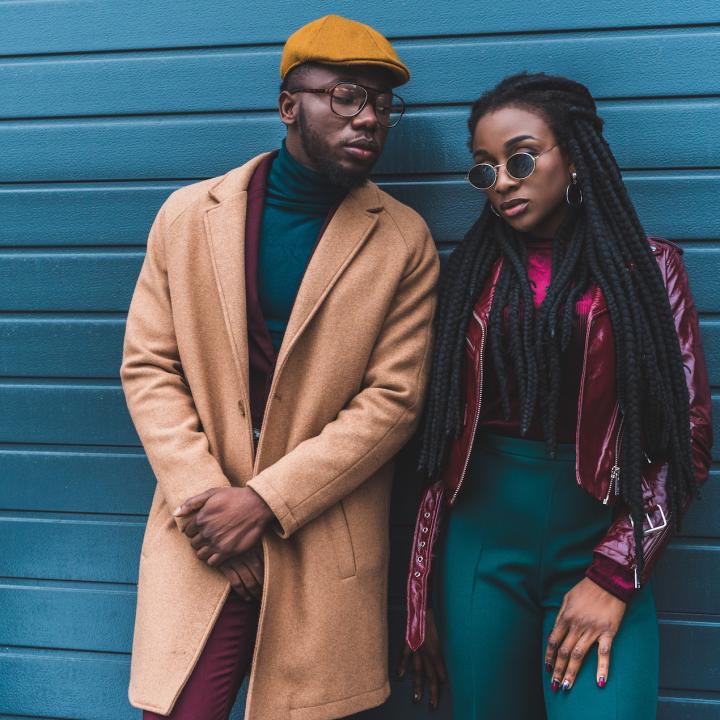 Hip African American couple leaning against blue wall