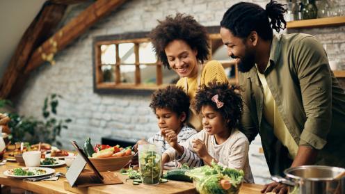 A happy family cooking veggies in a kitchen