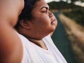 Up close photo of obese woman standing and relaxing after exercising outdoors