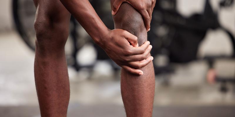 African American man rubbing sore knee