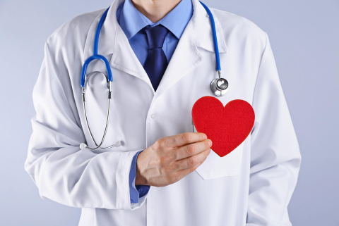 a doctor holding a red papercut heart shape