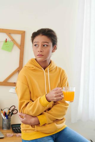 Sad teenage girl holding glass of orange juice