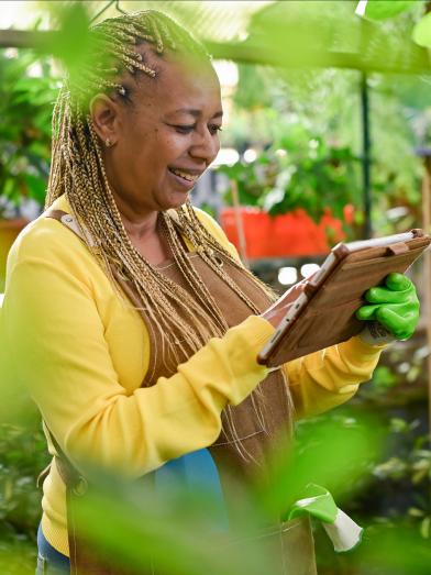African American woman in greenhouse looking at mobile device