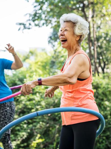 Senior women exercising outdoors with hula hoops
