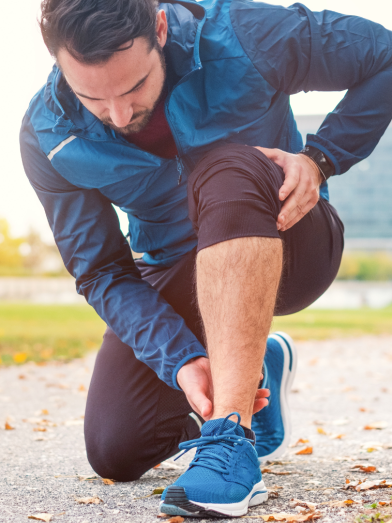 A man in workout clothes holds his hurting foot. 