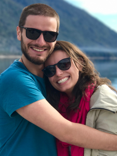 A couple hug while near a lake.